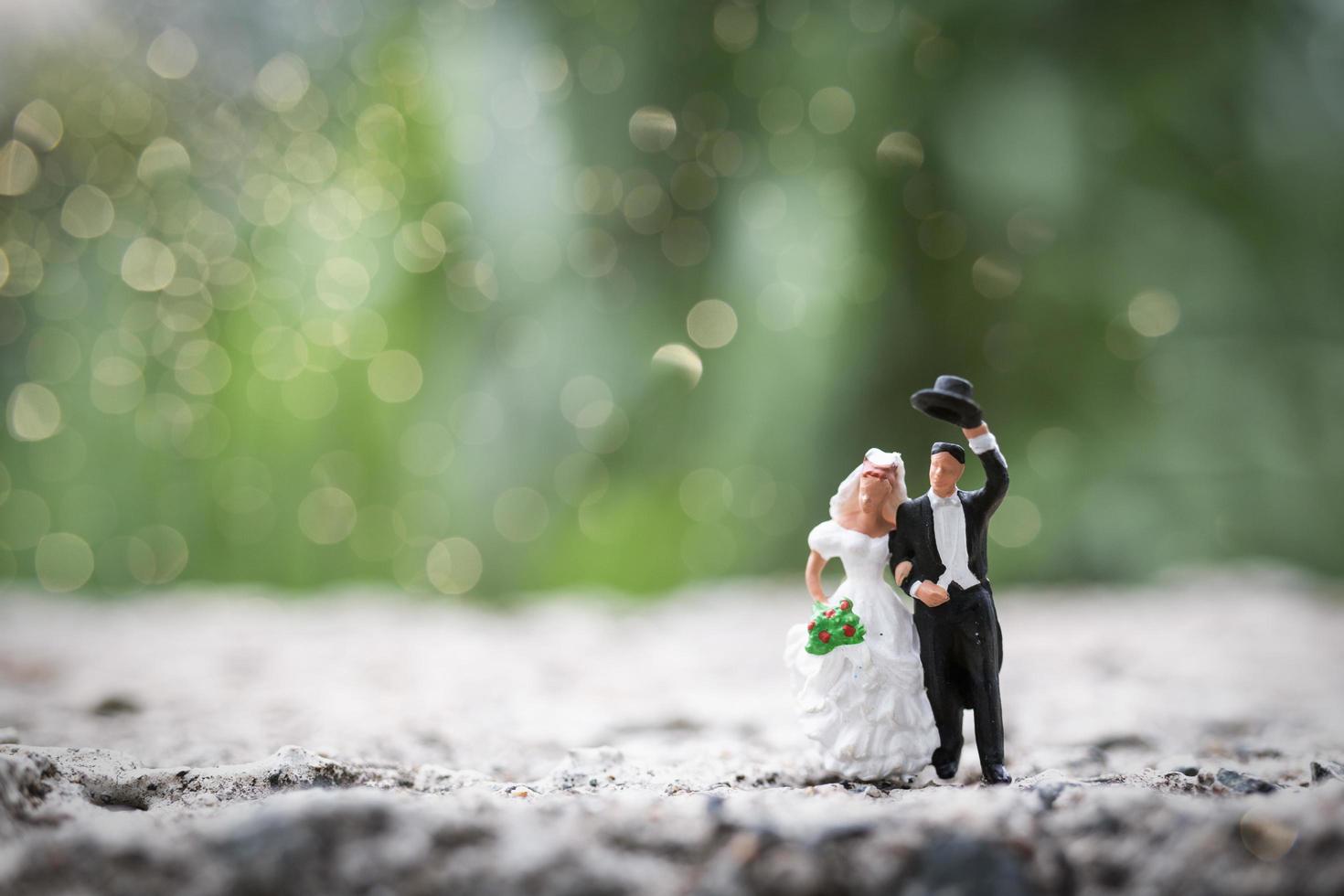 La novia y el novio en miniatura de pie al aire libre con un fondo de naturaleza borrosa foto