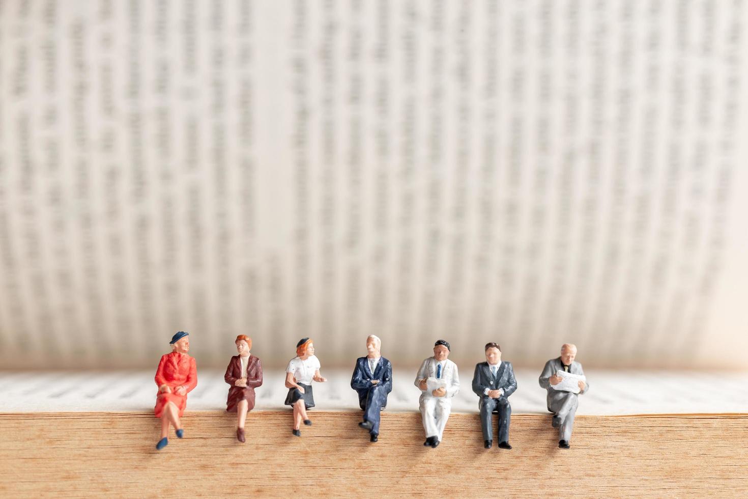 Miniature businesspeople sitting on an old book photo