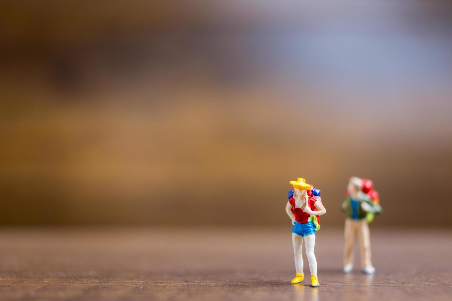 Miniature travelers standing on a wooden background, travel concept photo