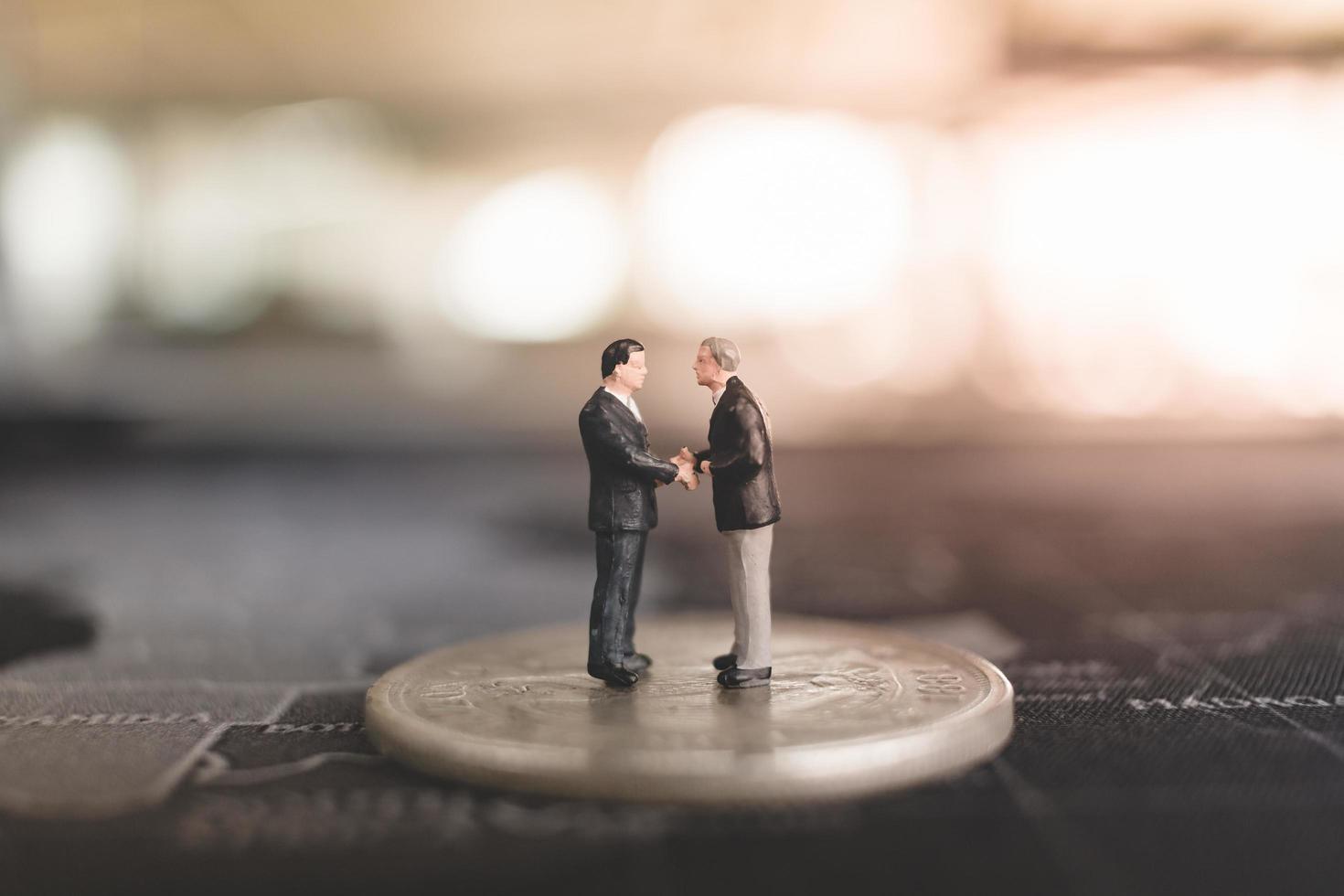 Miniature businessmen standing on a coin, business and finance concept photo