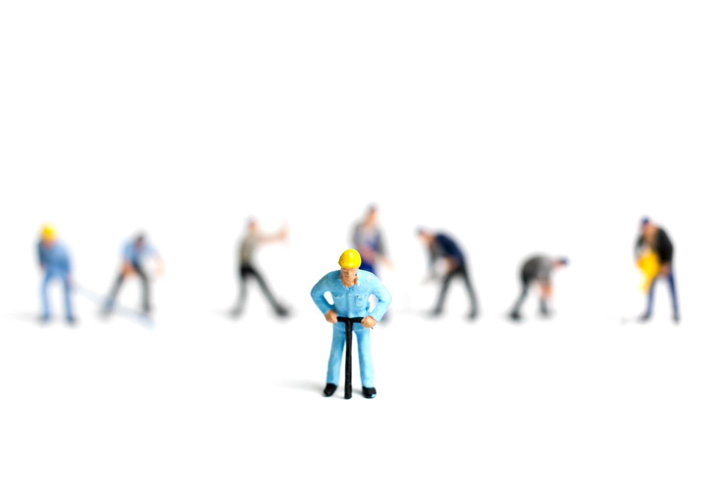 Miniature workers holding tools on a white background, construction concept photo