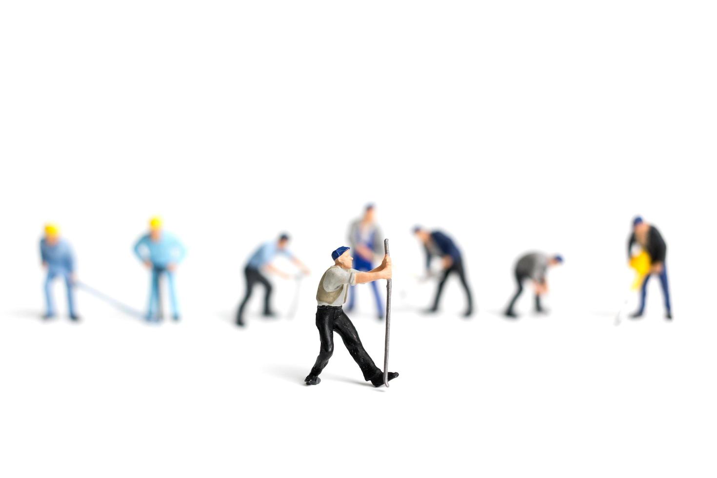 Miniature workers holding tools on a white background, construction concept photo