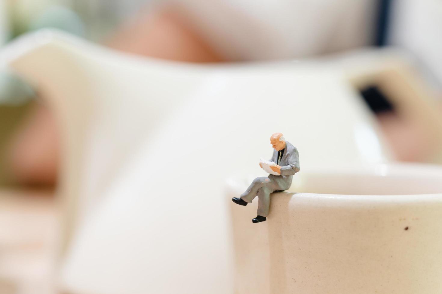 Empresario en miniatura sentado en una taza de té foto