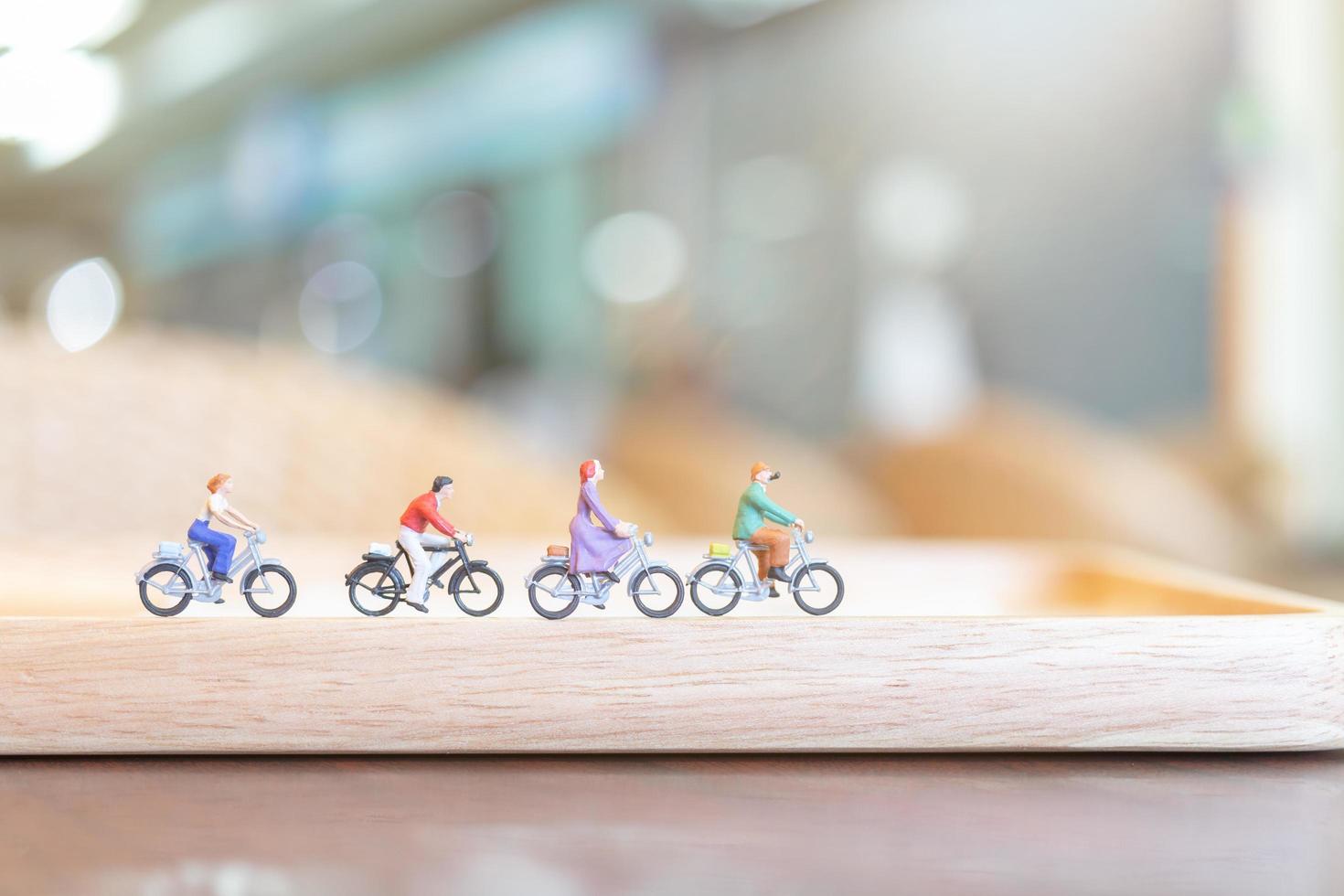 Gente en miniatura en bicicleta sobre un puente de madera, concepto de salud foto