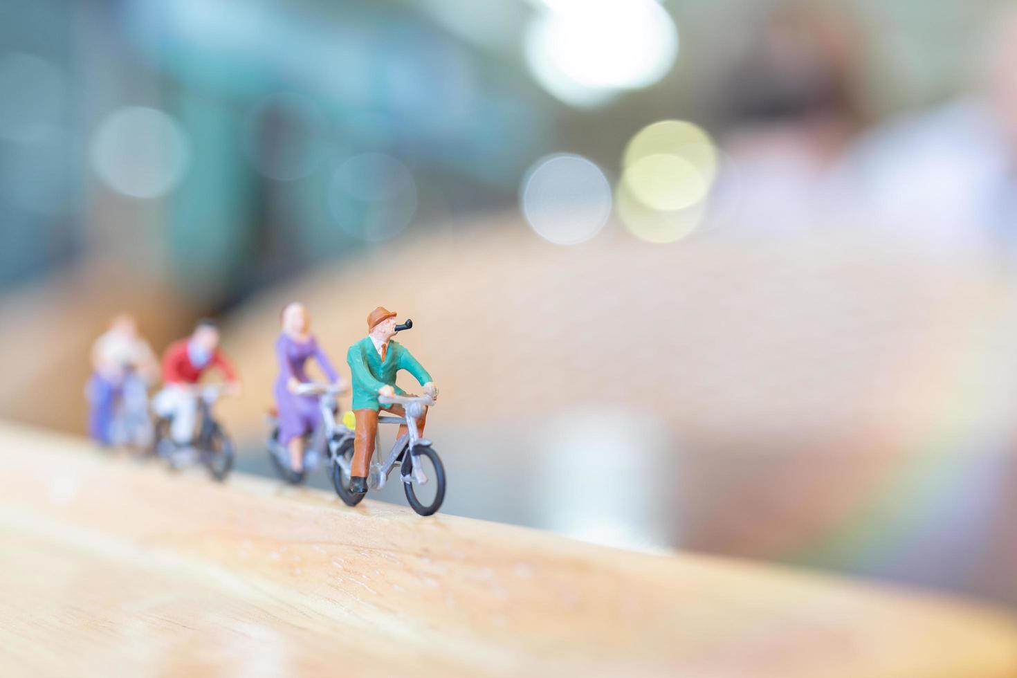 Gente en miniatura en bicicleta sobre un puente de madera, concepto de salud foto