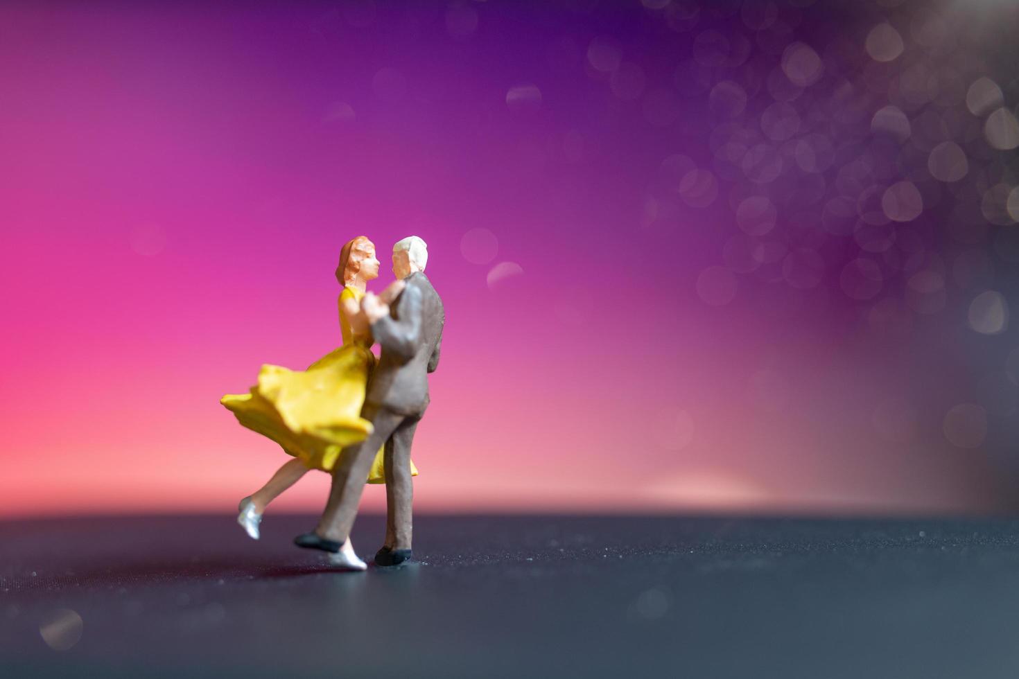 Pareja en miniatura bailando con un colorido fondo bokeh foto