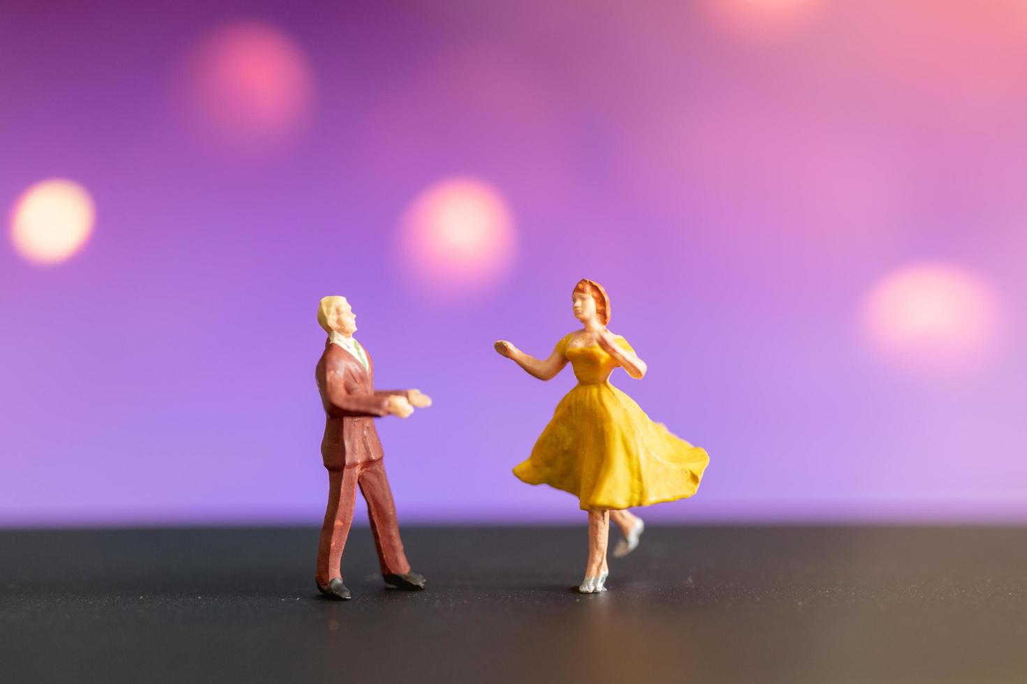 Pareja en miniatura bailando con un colorido fondo bokeh foto