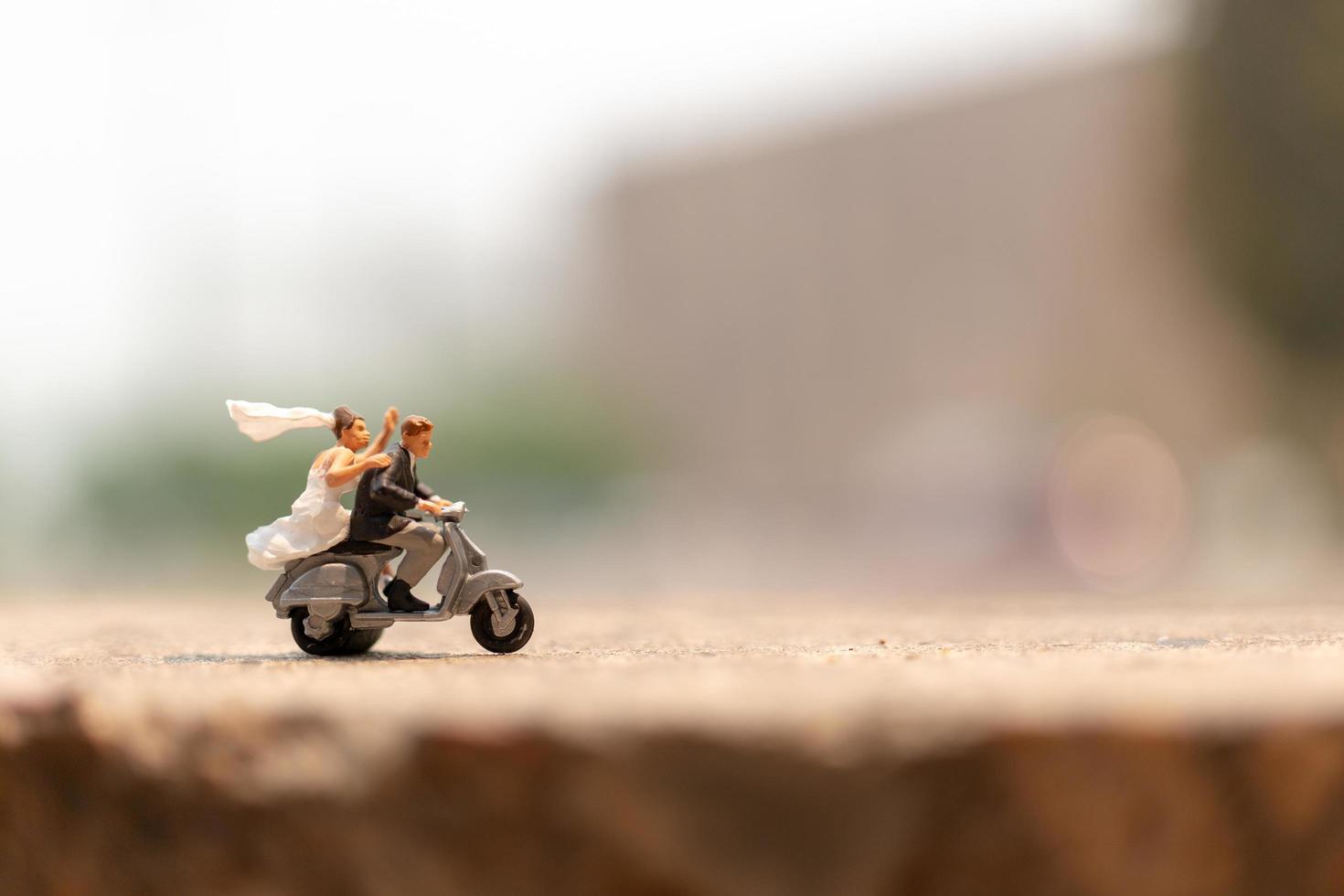 Miniature couple riding a motorcycle in a garden photo