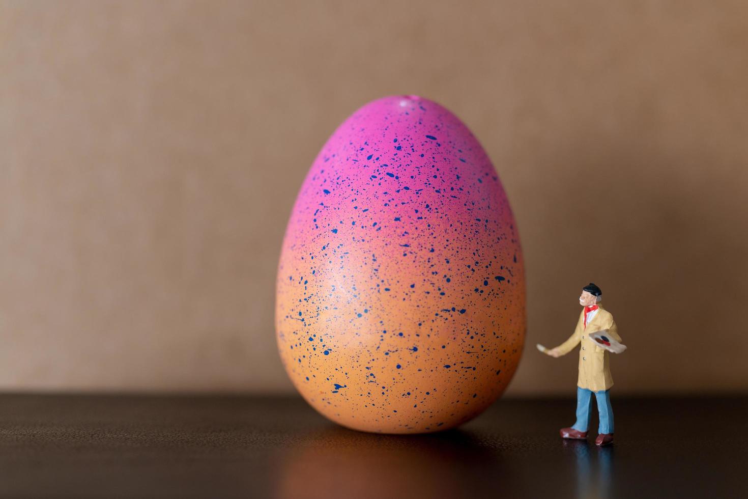 Artista en miniatura sosteniendo un pincel y pintando huevos de pascua para pascua foto