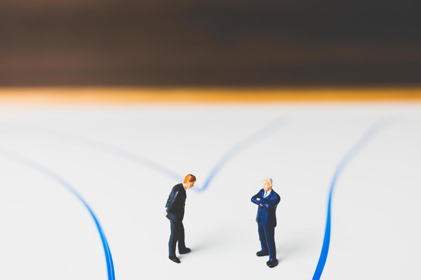 Miniature businessmen standing on an arrow pathway, business decision concept photo