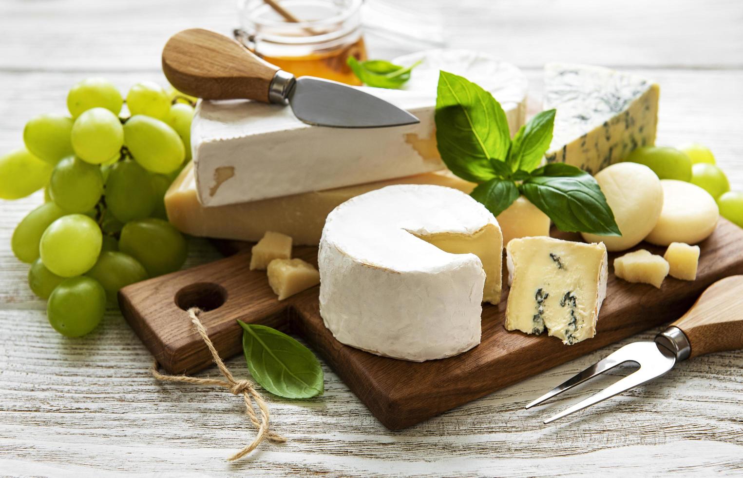 Various types of cheese on a white wooden background photo