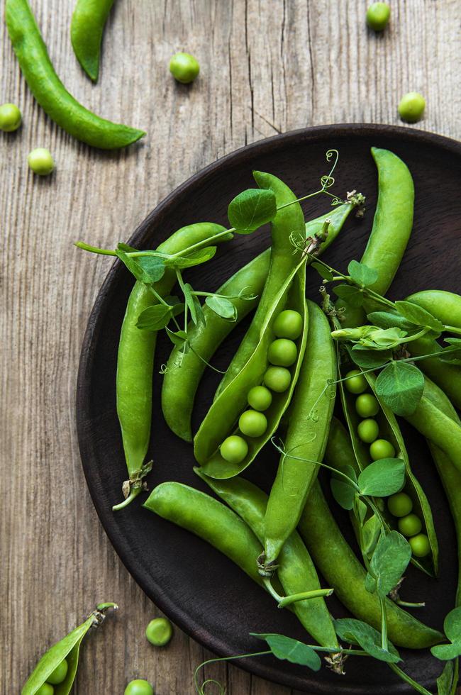 Green peas on a plate on a old wooden background photo