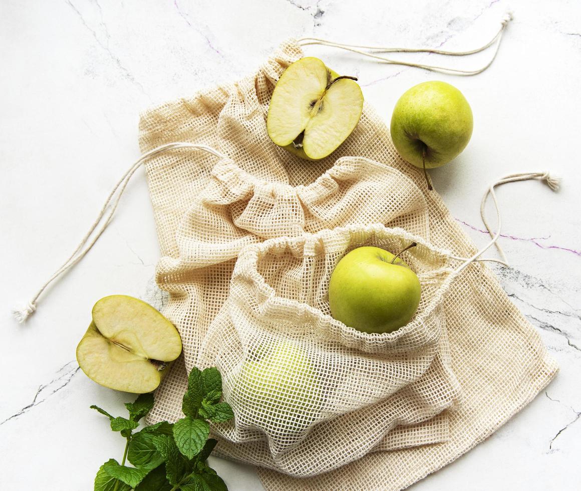 Manzanas verdes frescas en bolsas de malla, vista superior foto