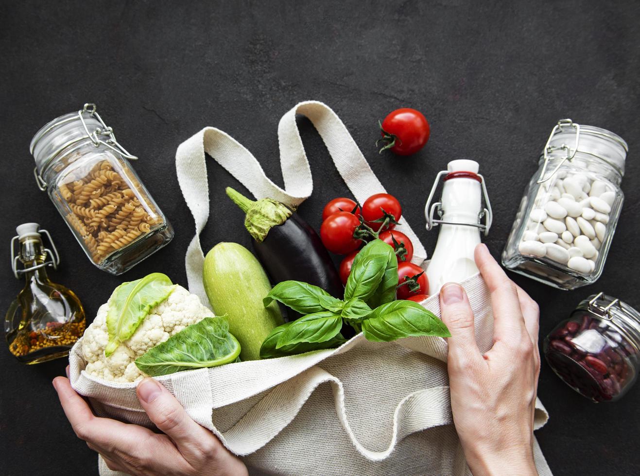 Eco bag with fruits and vegetables, glass jars with beans, pasta photo