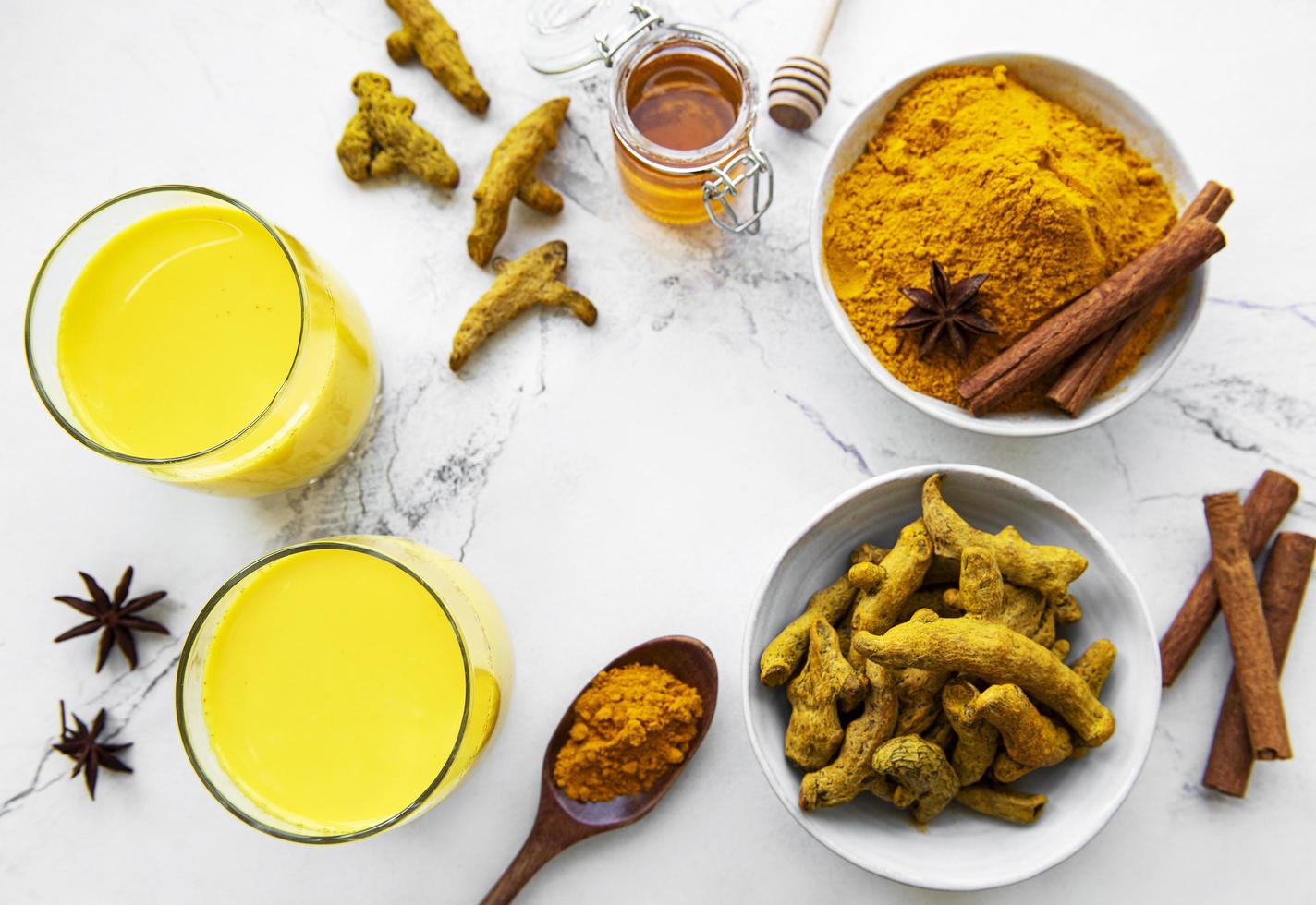 Golden milk with cinnamon, turmeric, ginger  and honey over white wooden background. photo