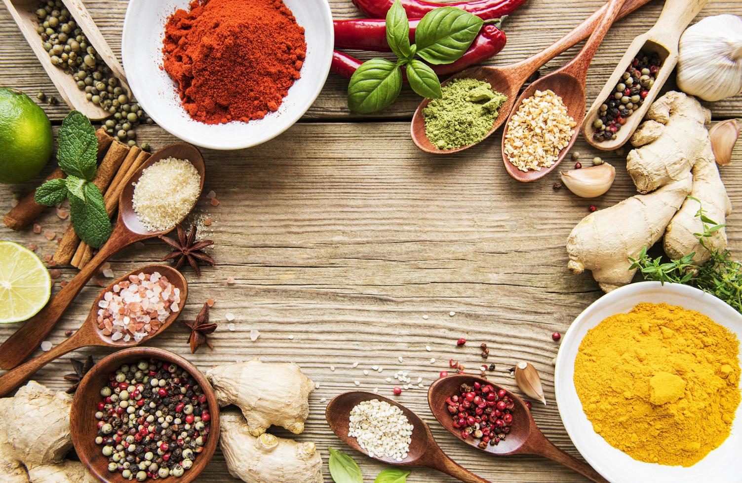 A selection of various colorful spices on a wooden table in bowls and spoons photo