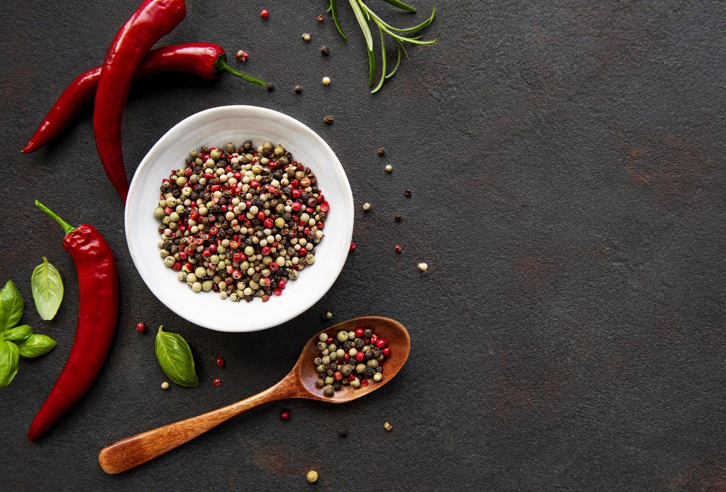 Red hot chili pepper corns and pods on dark background, top view photo