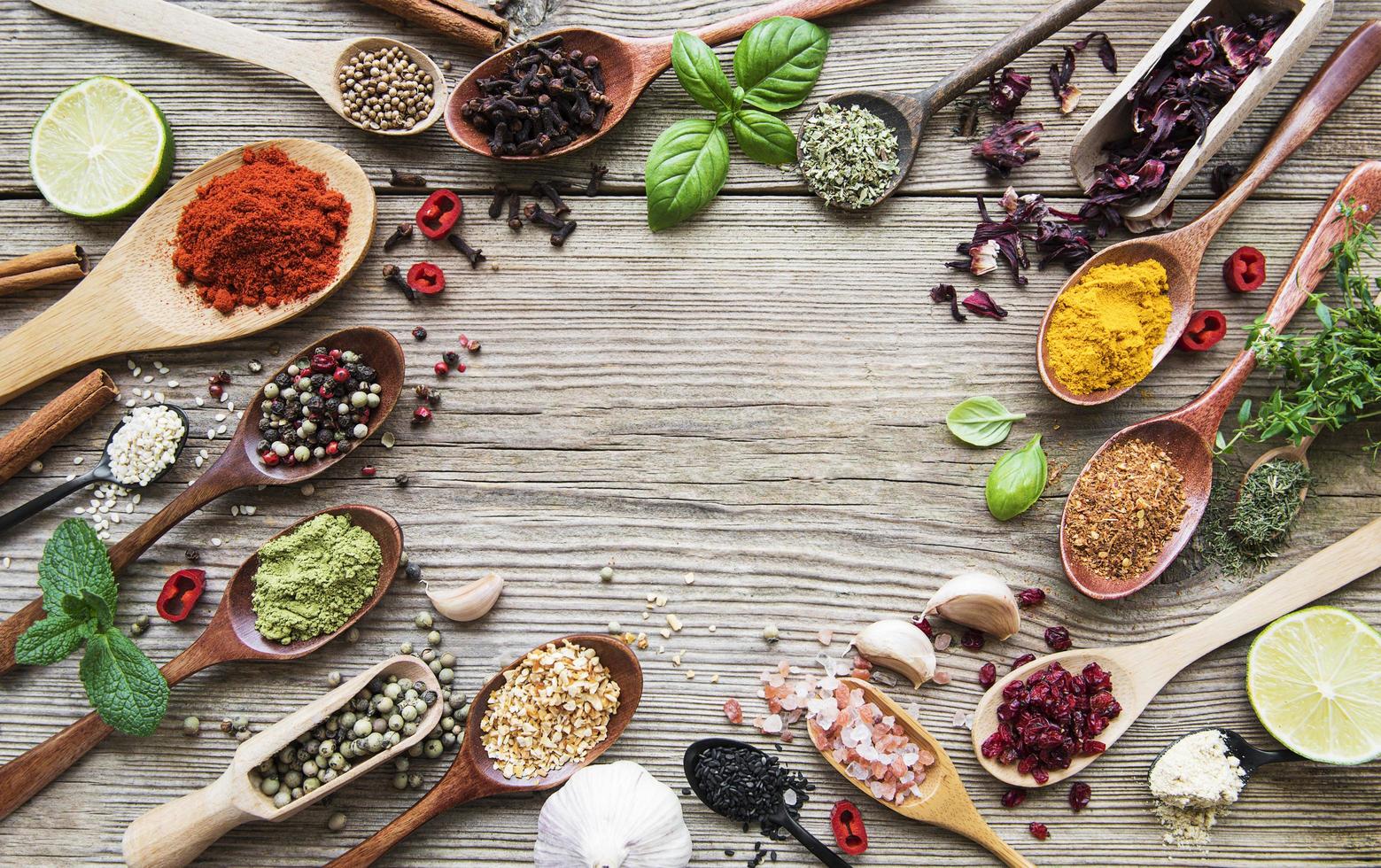 A selection of various colorful spices on a wooden table in spoons photo