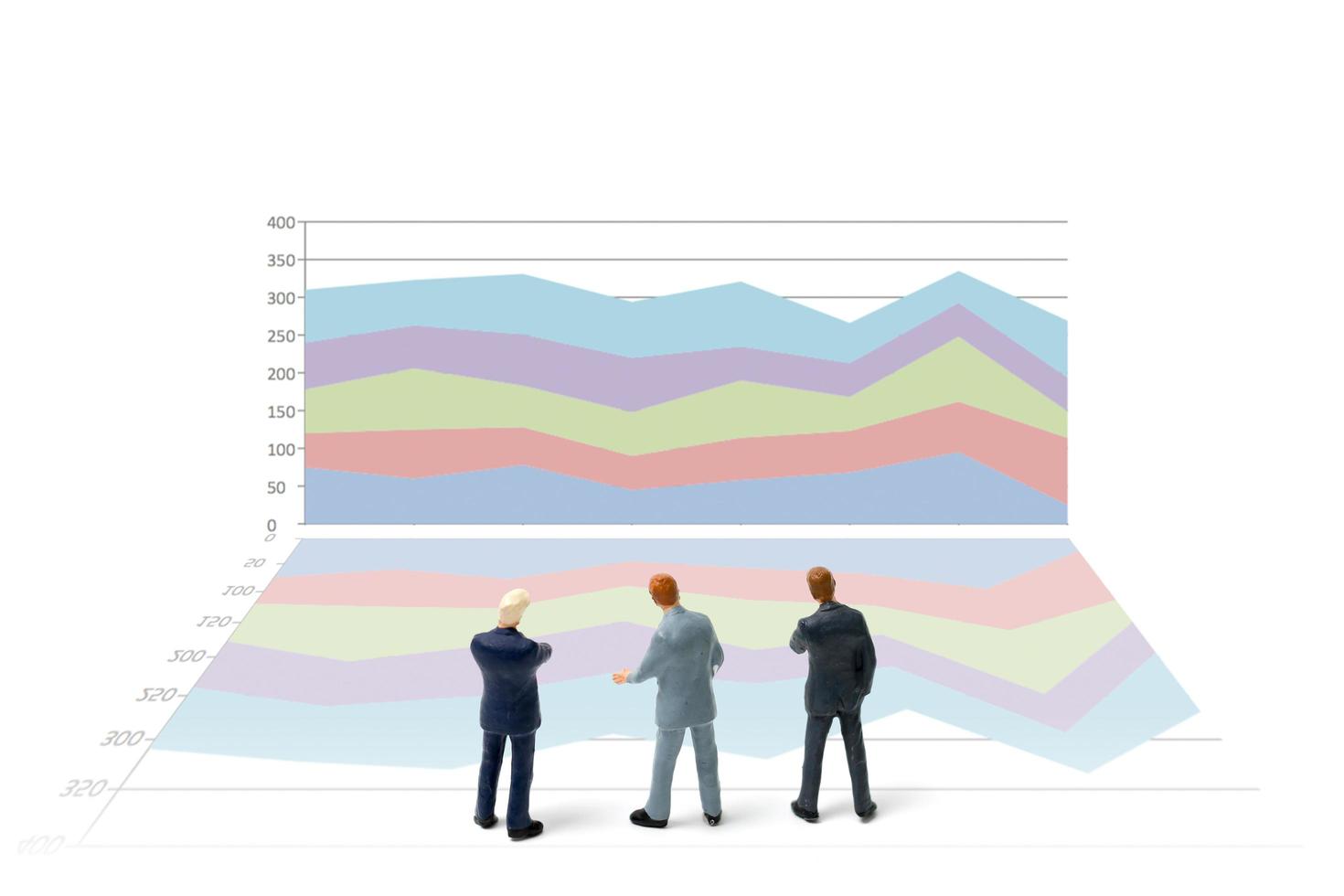 Miniature businessmen standing with charts on a white background photo