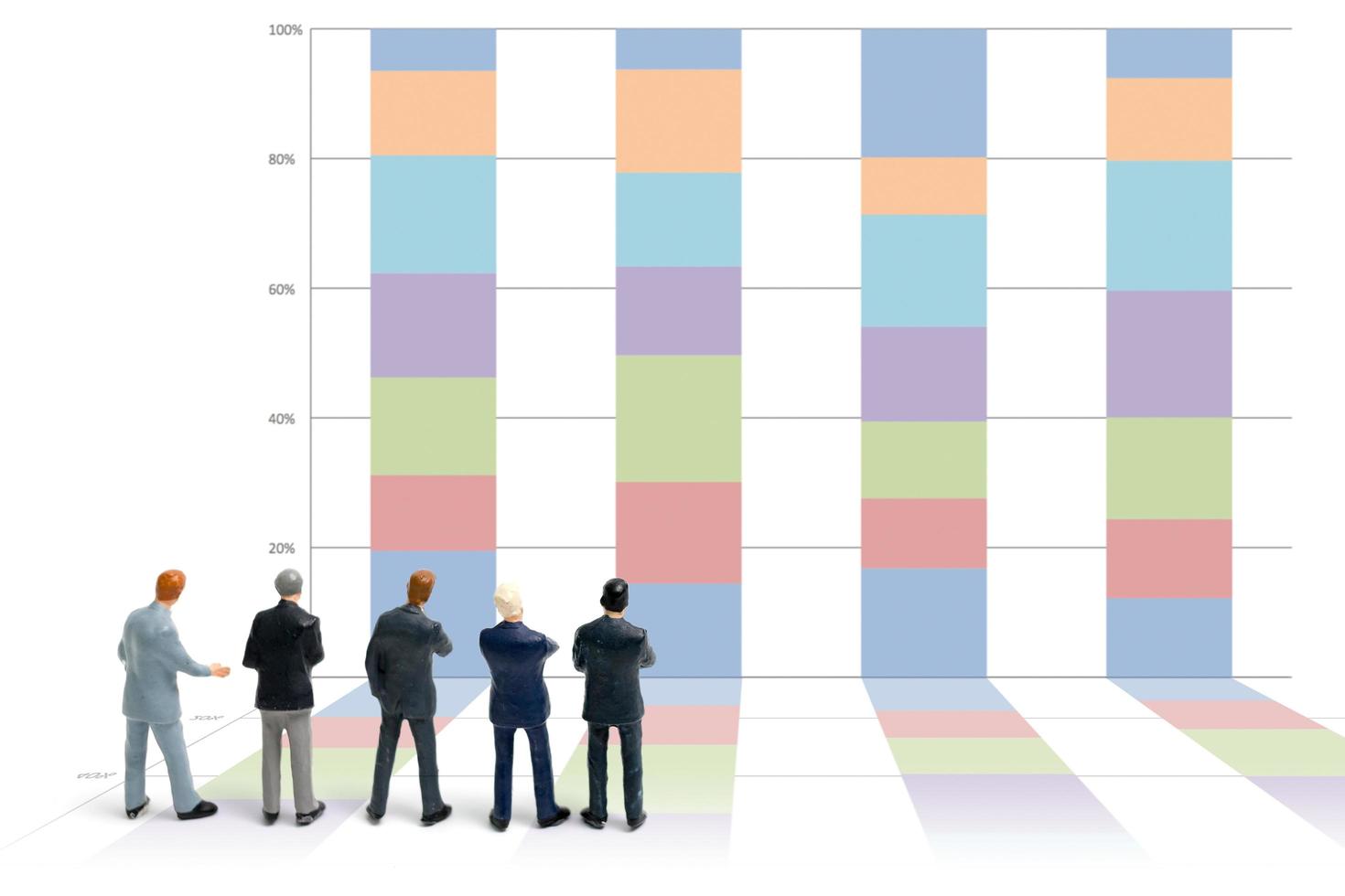 Miniature businessmen standing with charts on a white background photo