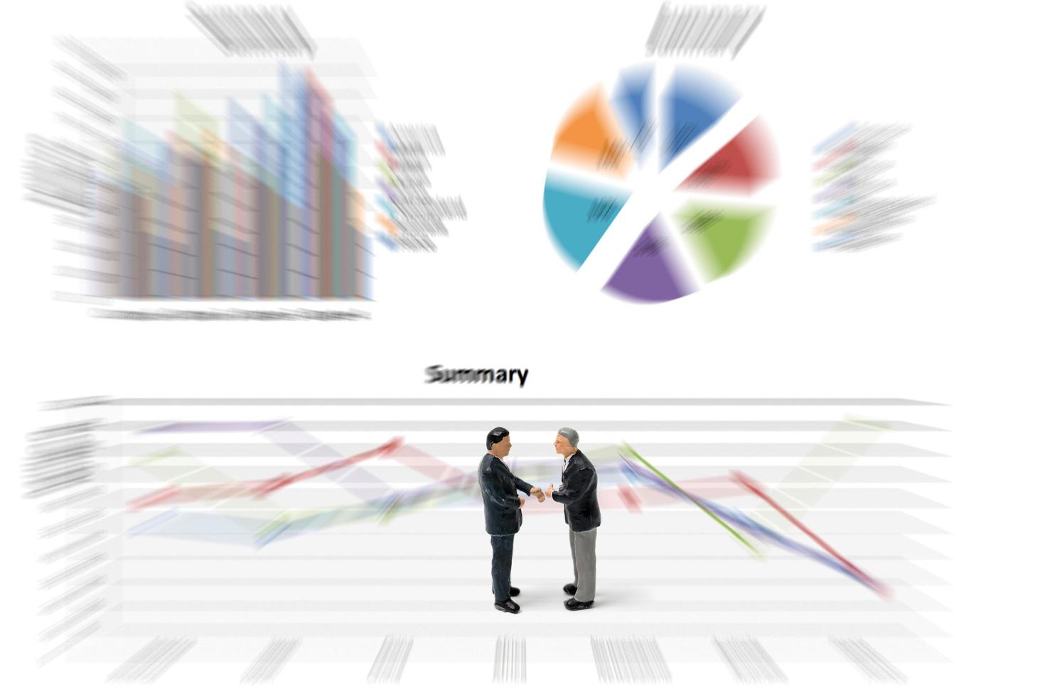 Miniature businessmen standing with charts on a white background photo