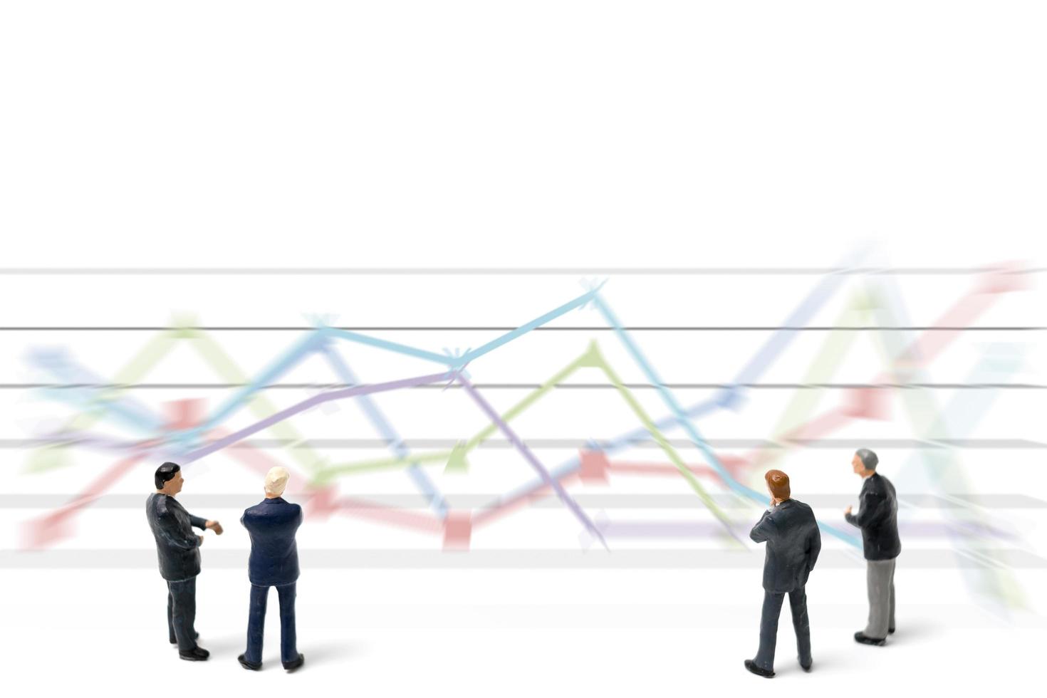 Miniature businessmen standing with charts on a white background photo