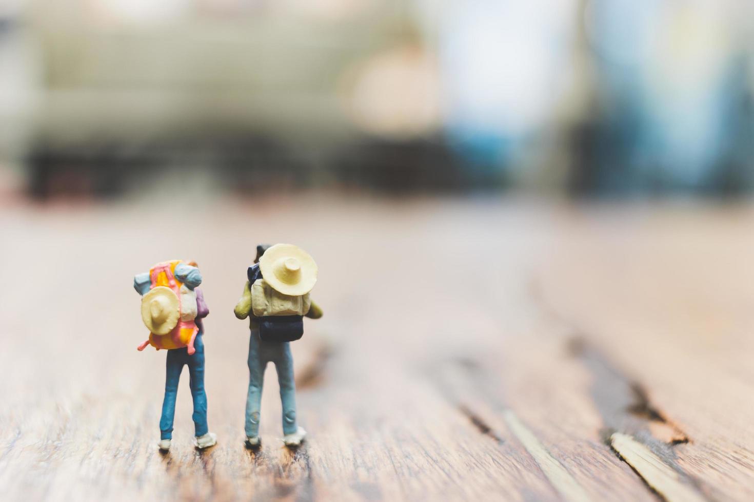 Turistas mochileros en miniatura gente de pie sobre un fondo borroso de madera foto