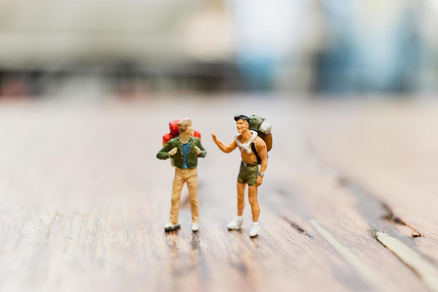 Miniature backpacker tourist people standing on a wooden blurred background photo