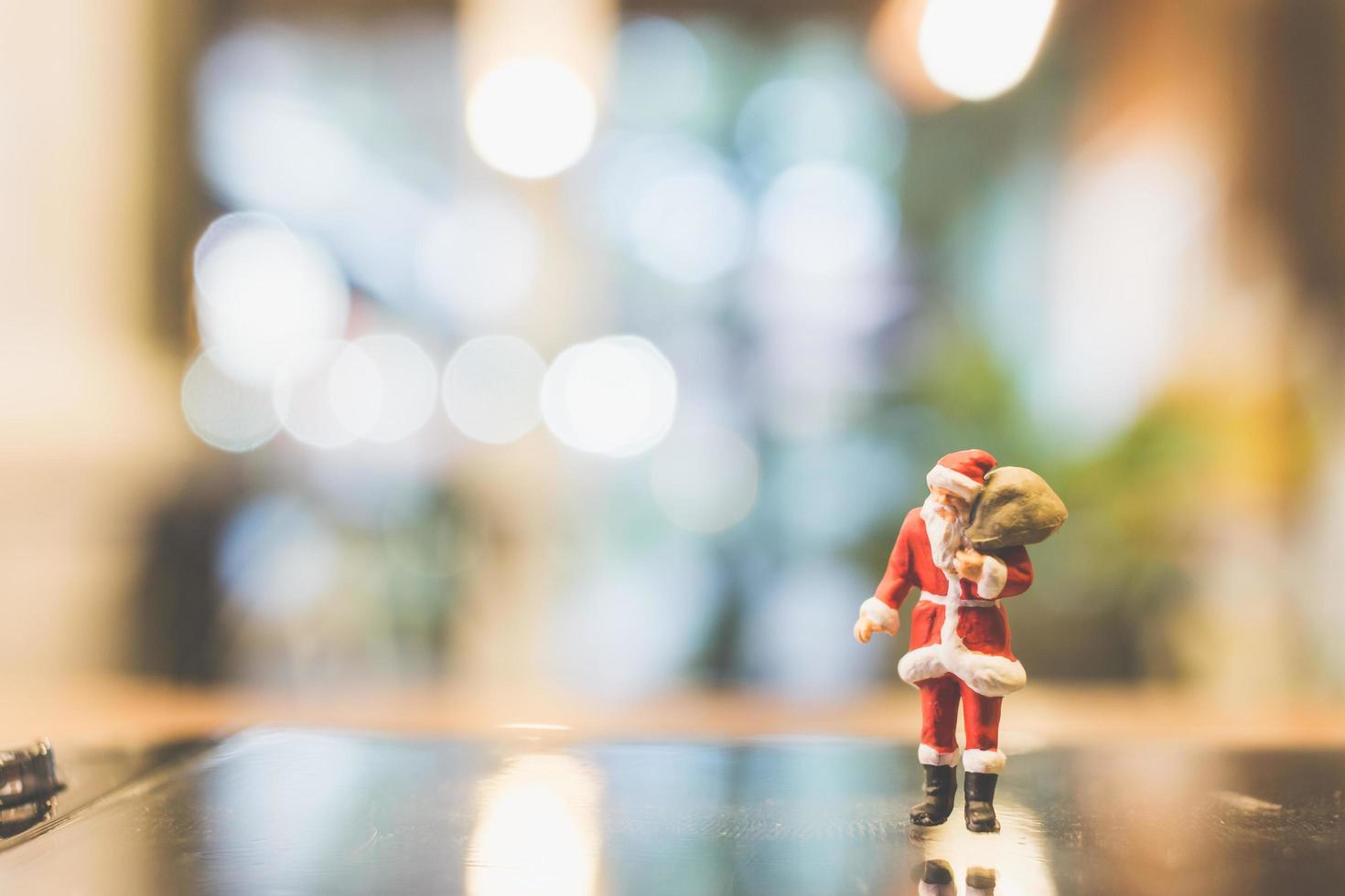 Papá Noel en miniatura de pie sobre el vidrio con un fondo borroso foto