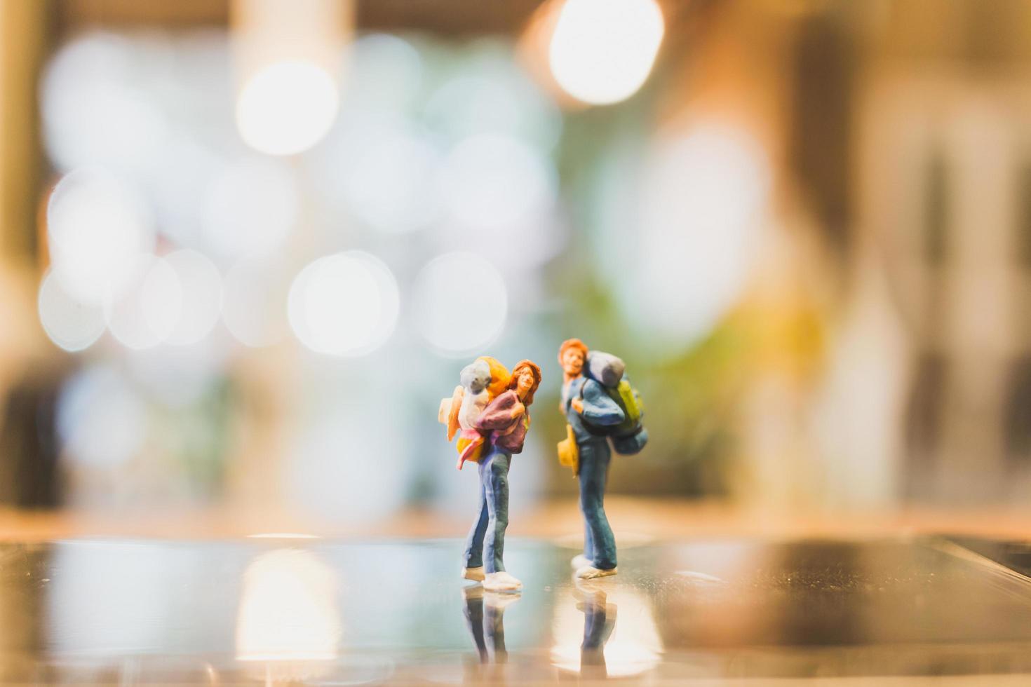 Miniature backpacker tourist people standing on glass with a blurred background photo