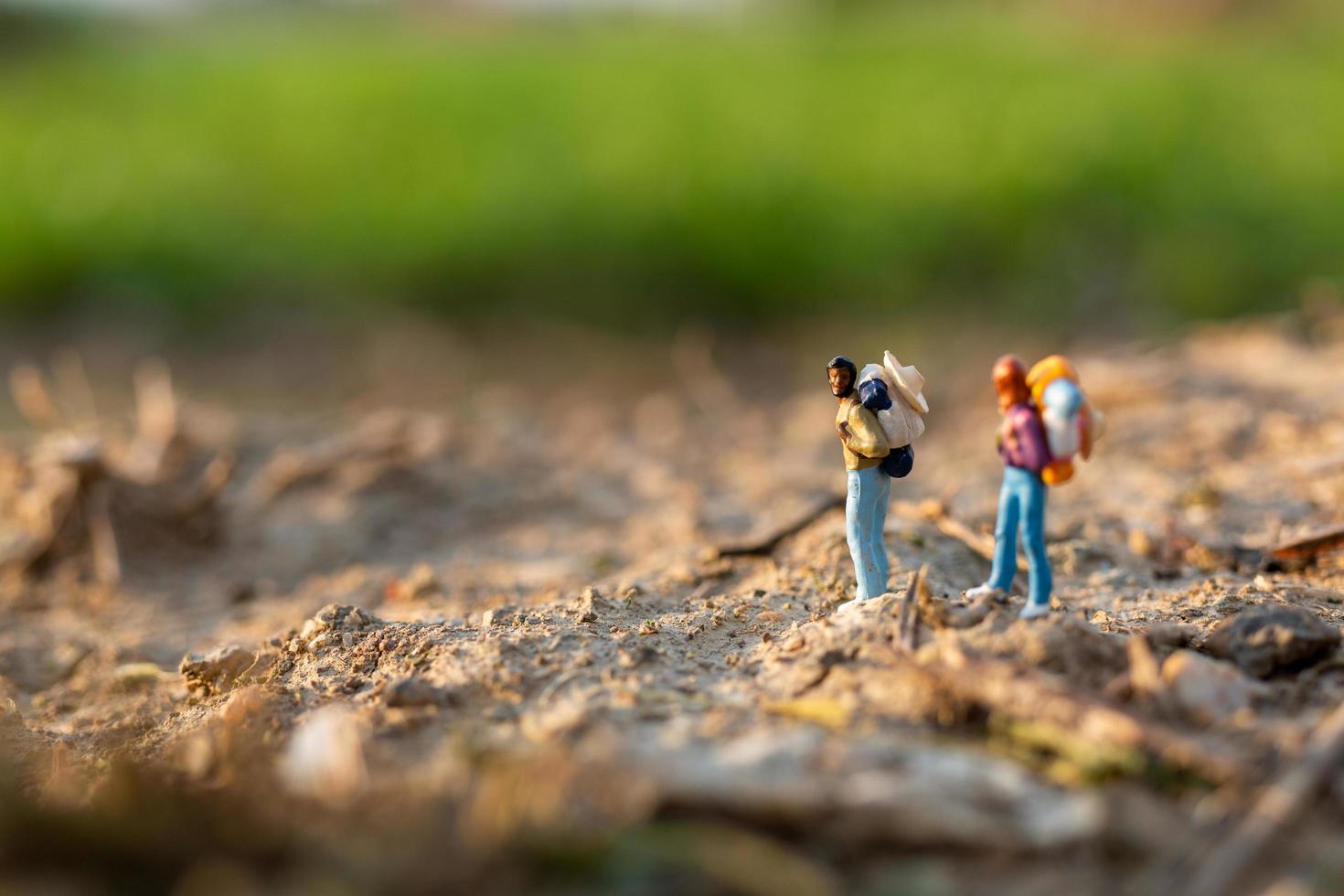 Viajeros en miniatura con mochilas caminando en un concepto de pradera, viajes y aventuras foto