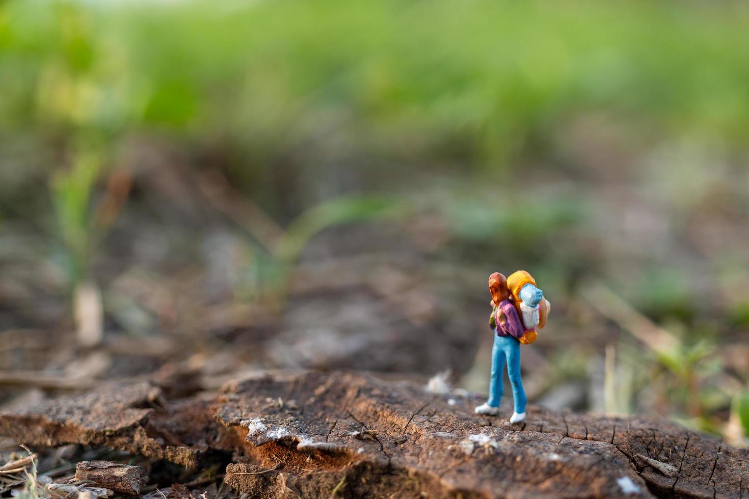 Viajero en miniatura con una mochila caminando en un prado, concepto de viaje y aventura foto