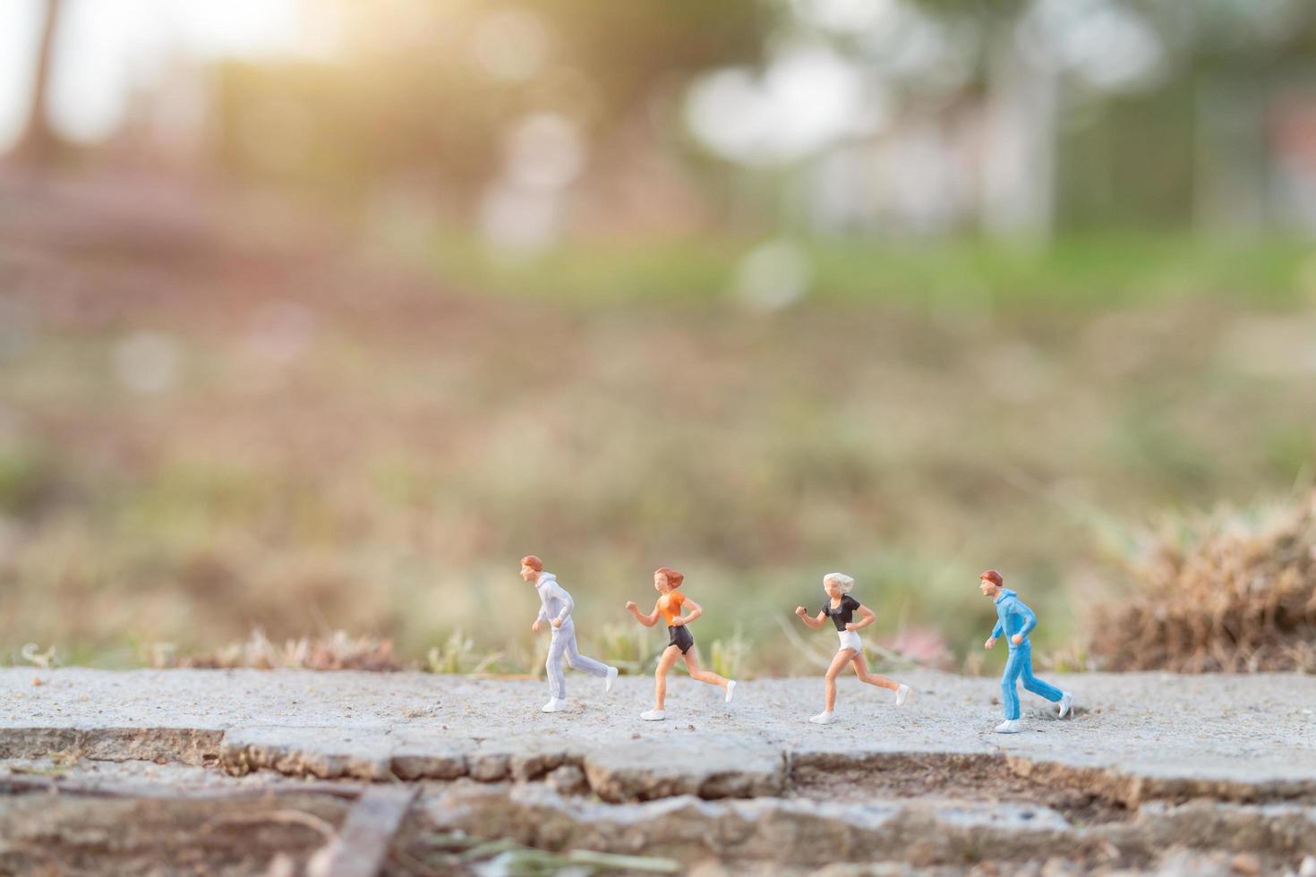 Gente en miniatura corriendo en una carretera con un fondo de naturaleza, concepto de salud y estilo de vida foto