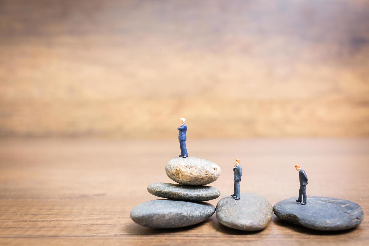 Empresarios en miniatura de pie sobre una piedra, concepto de desafíos y riesgos foto