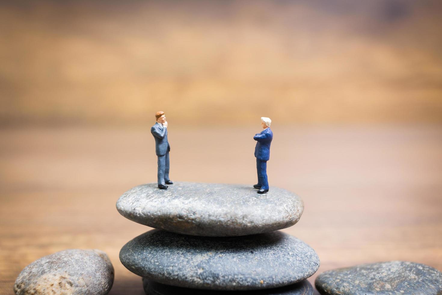Empresarios en miniatura de pie sobre una piedra, concepto de desafíos y riesgos foto