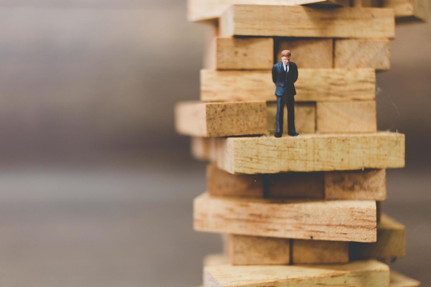 Miniature businessman standing on woodblocks photo