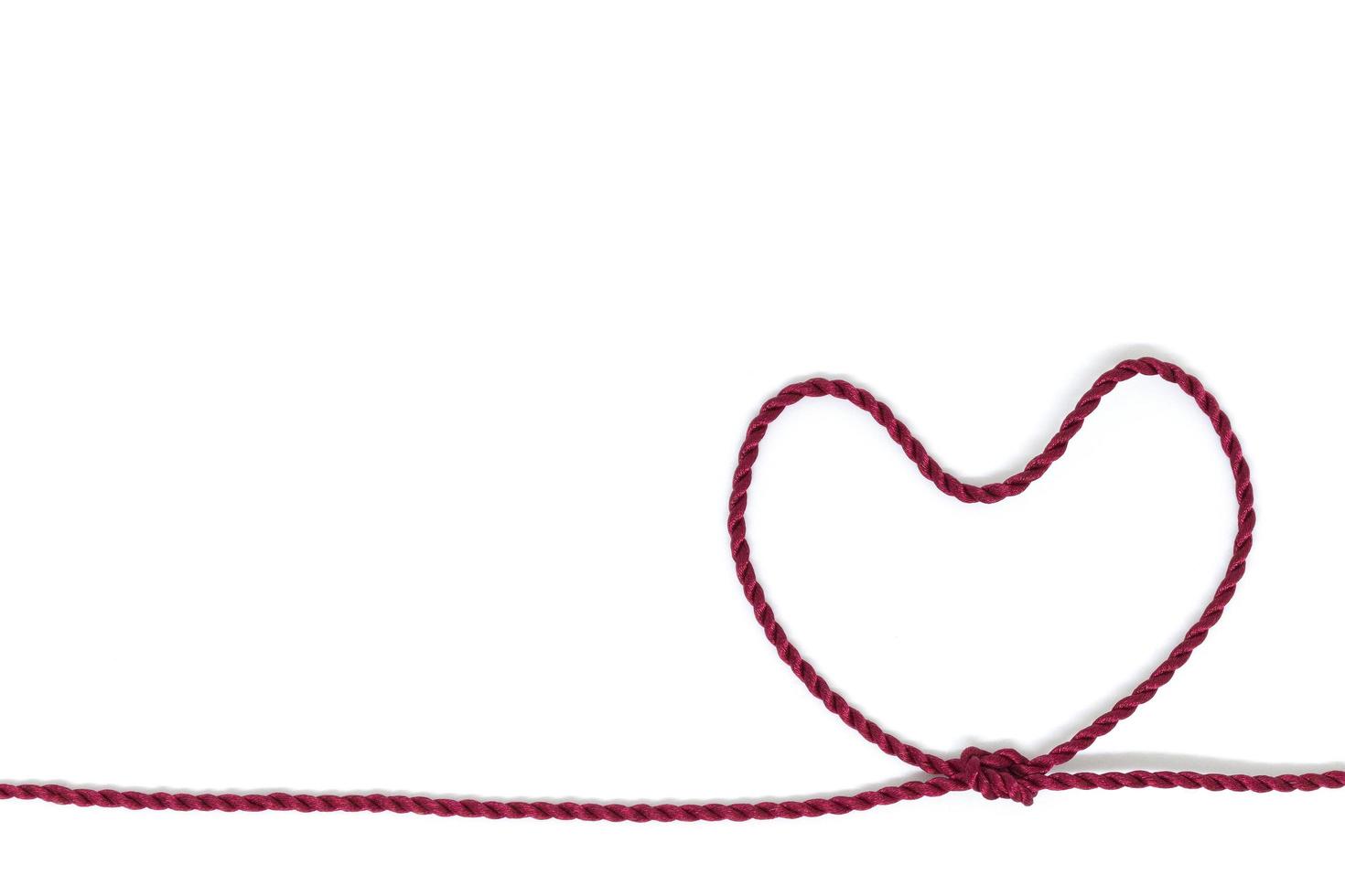 Nudo en forma de corazón en una cuerda sobre un fondo blanco. foto