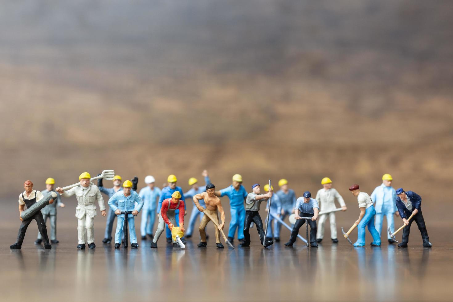 Miniature group of workers holding tools on a wooden background photo