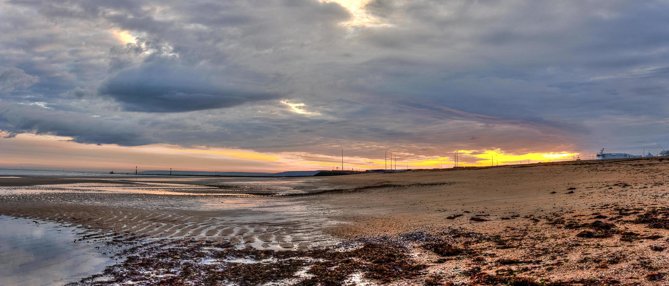 Colorido amanecer nublado cielo en una playa en Normandía, Francia foto