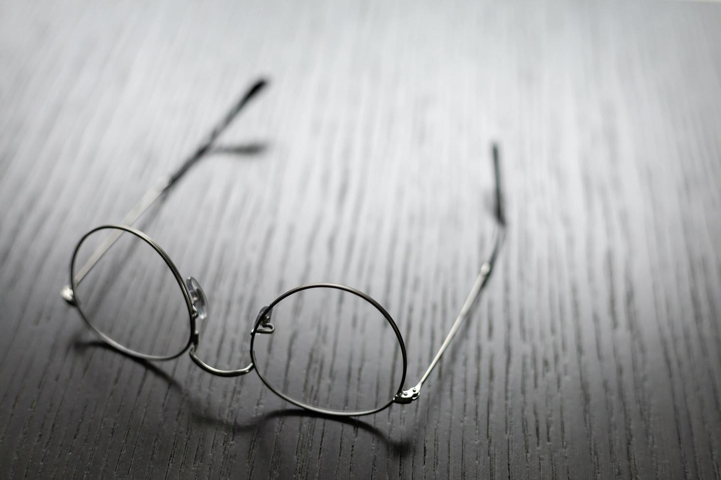 Gafas de estructura metálica acostada boca abajo sobre una mesa de madera foto