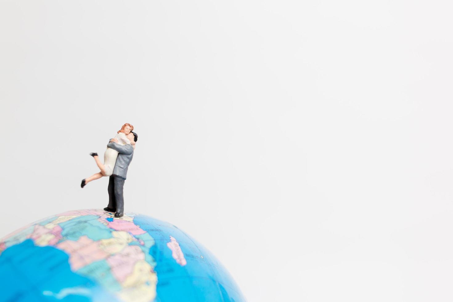 Gente en miniatura de pie sobre un globo terráqueo con un fondo blanco, concepto de viaje foto