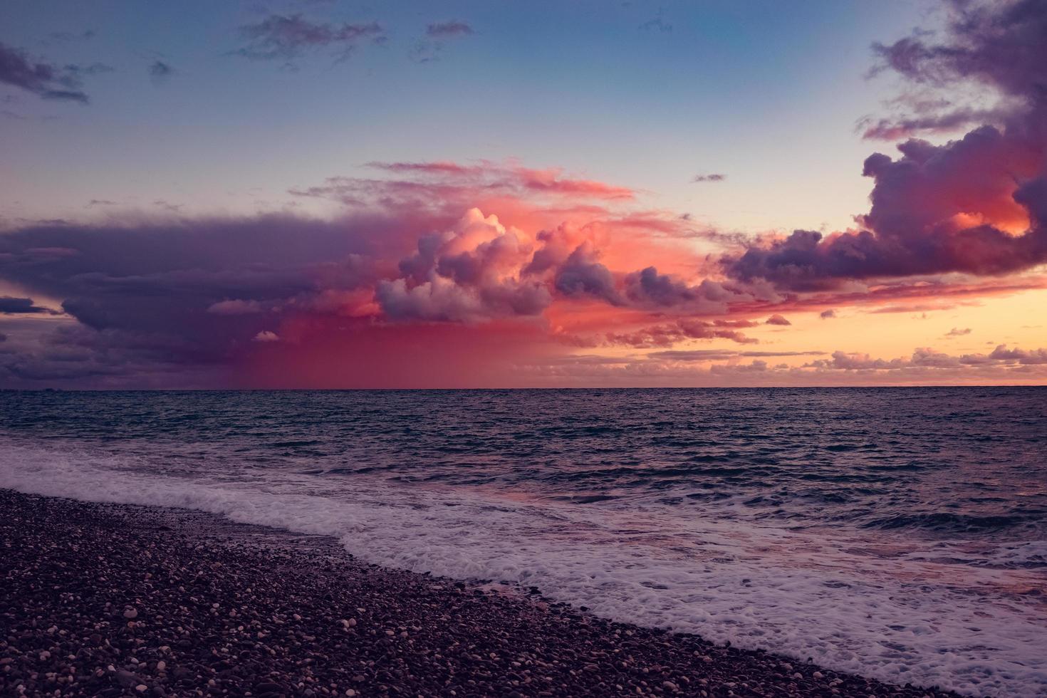 paisaje marino de playa y cuerpo de agua con un colorido atardecer nublado foto