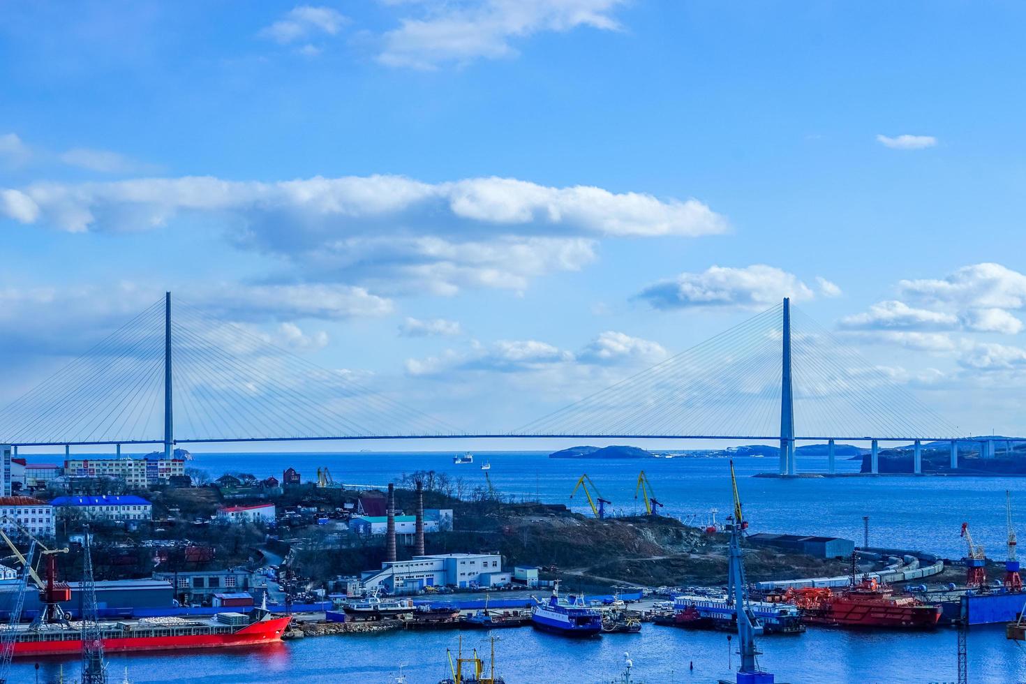 Paisaje urbano de un puerto y el puente ruso con un nublado cielo azul en Vladivostok, Rusia foto