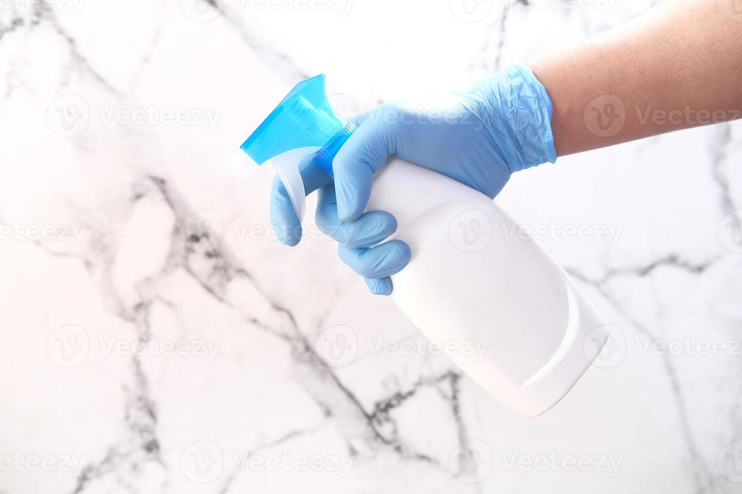 La mano de la persona en guantes desechables con spray desinfectante foto