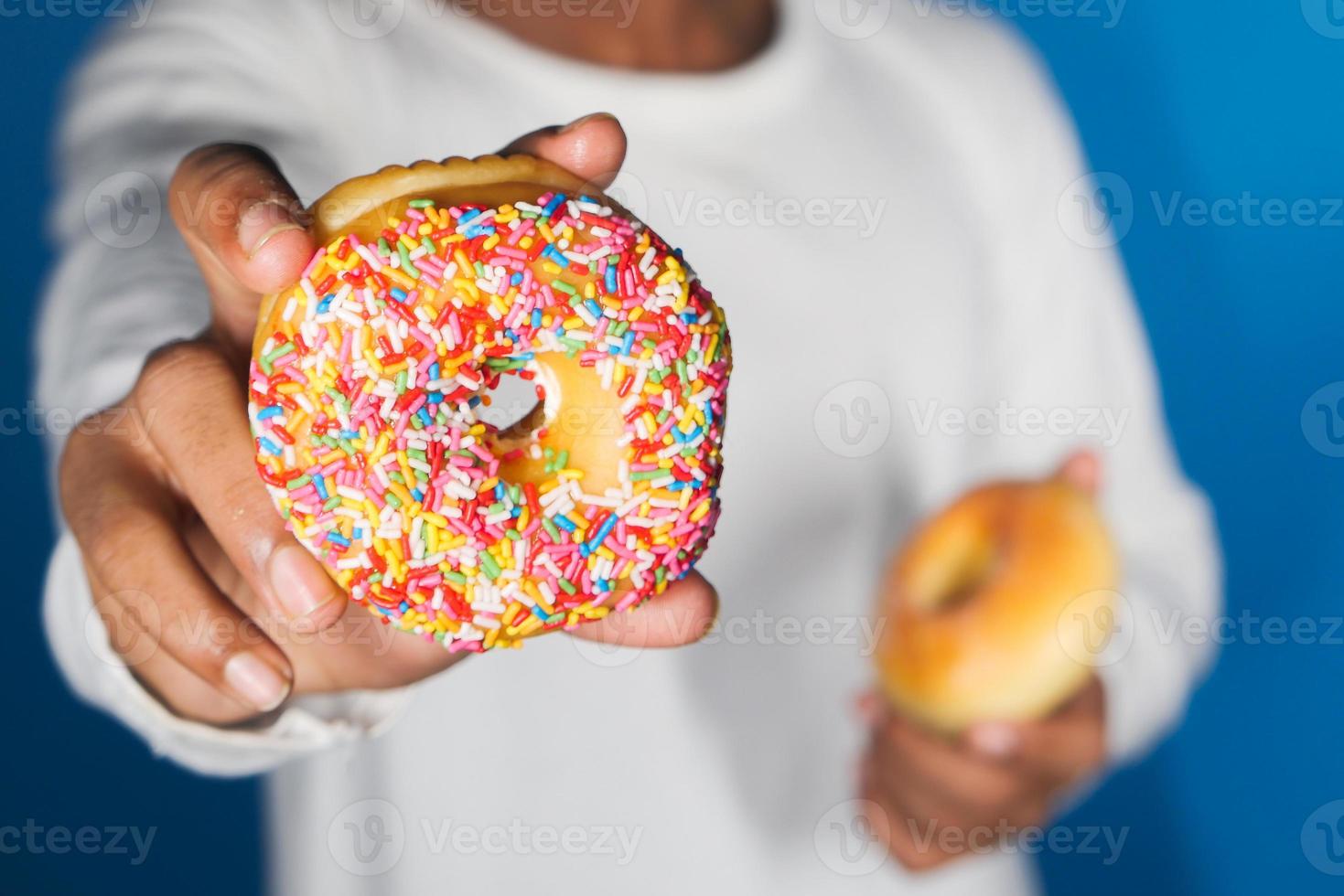 Close up of hand holding donuts on blue background photo