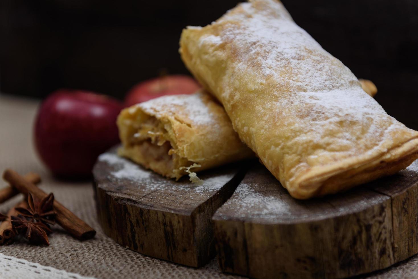 Apple strudel on wooden end of a tree with apples, cinnamon and star anise photo