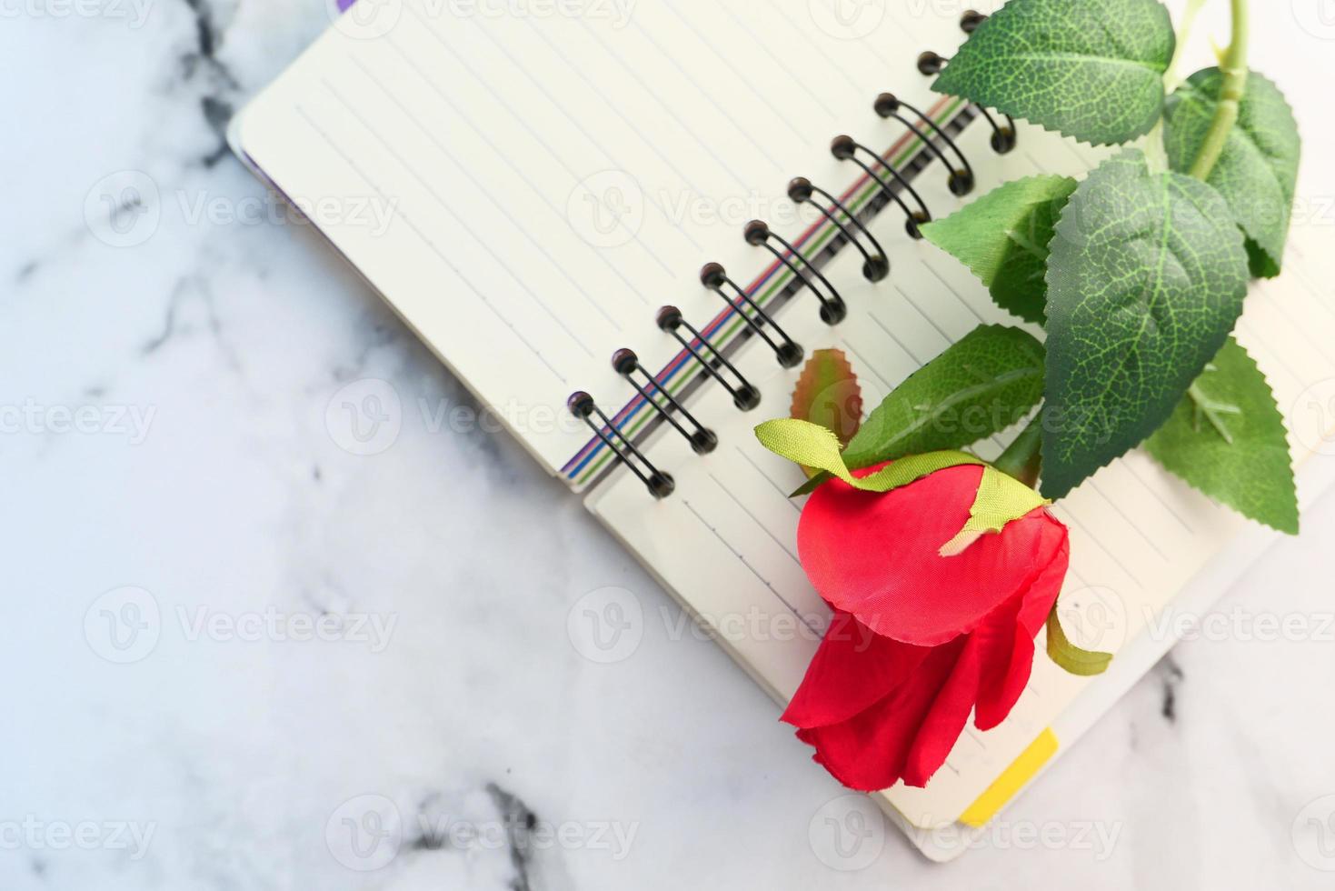 Red rose flower on notepad on table photo