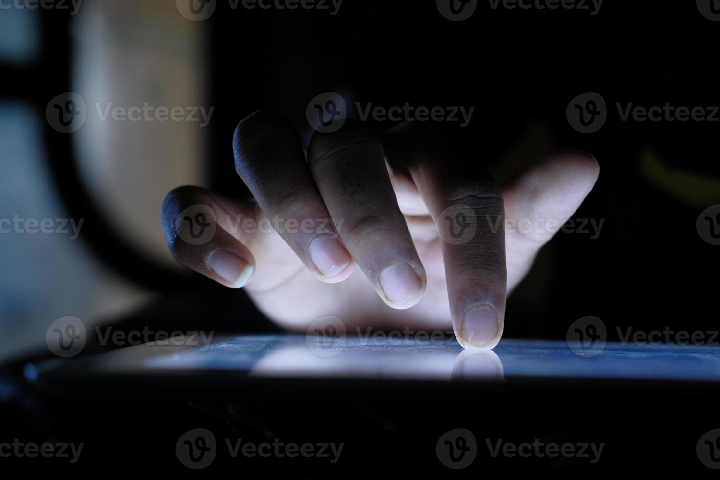 Close up of hand using tablet in the dark photo