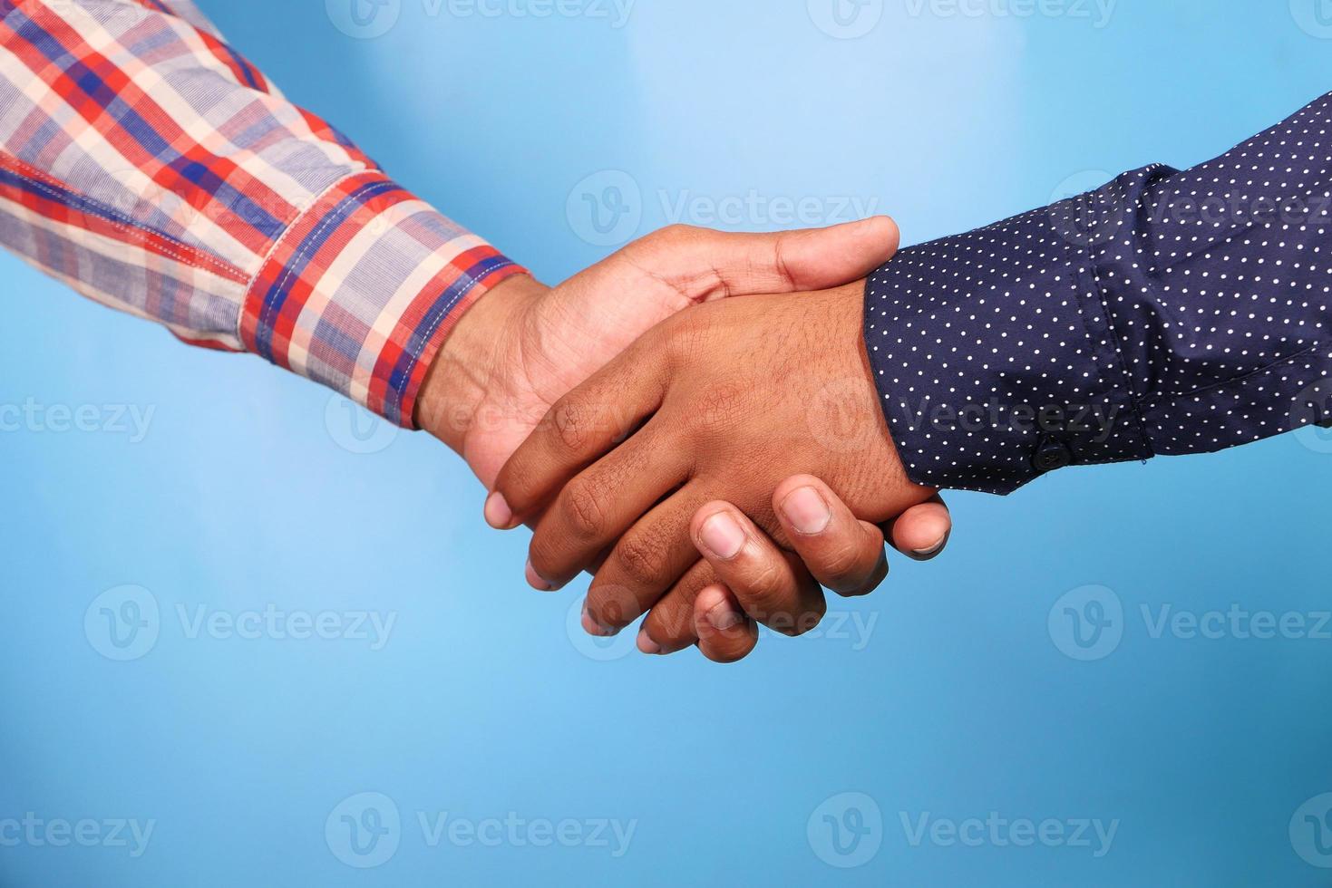 Two people shaking hands against blue background photo