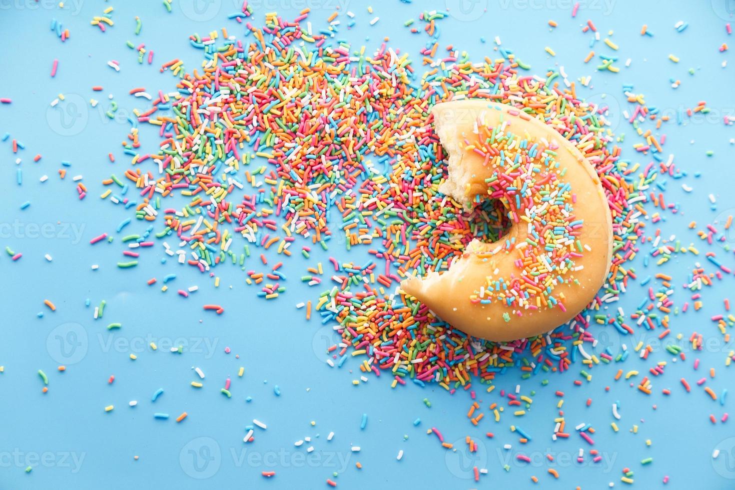Colorful donuts with sprinkles on blue background top down photo
